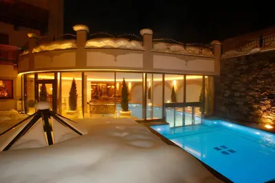 a lobby with chairs and a bar in a building at Savoy Dolomites Luxury & Spa Hotel in Selva di Val Gardena