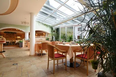 a conservatory with a table and chairs and plants at B&B Appartments Cudlea in Selva di Val Gardena