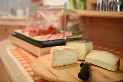 a cutting board with three pieces of cheese on a counter at B&B Appartments Cudlea in Selva di Val Gardena