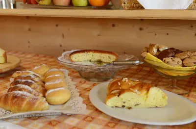 a table topped with plates of pastries and bread at B&B Appartments Cudlea in Selva di Val Gardena