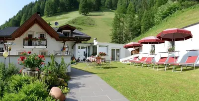 a group of chairs and umbrellas in front of a house at B&B Appartments Cudlea in Selva di Val Gardena