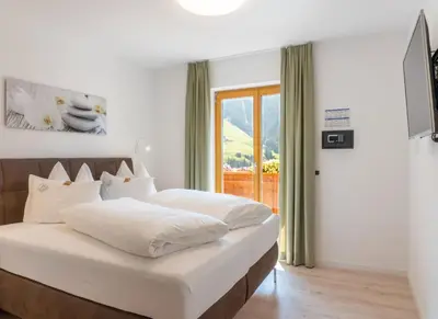 a bedroom with a bed with white sheets and a window at Residence Töglhof in Funes