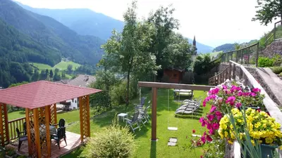 a garden with tables chairs and flowers on a balcony at Residence Töglhof in Funes