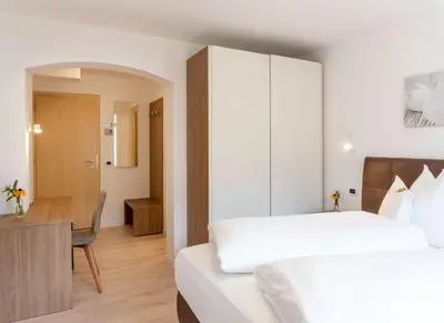 a hotel room with two beds and a desk at Residence Töglhof in Funes