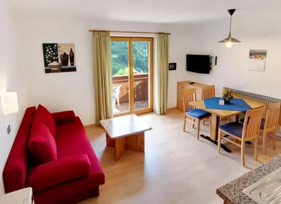 a living room with a red couch and a table at Residence Töglhof in Funes