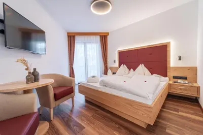 a hotel room with a large bed and a table at Hotel Meinhardt in Schenna