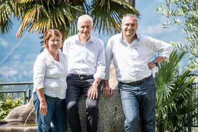 two men and a woman sitting on a tree at Hotel Meinhardt in Schenna