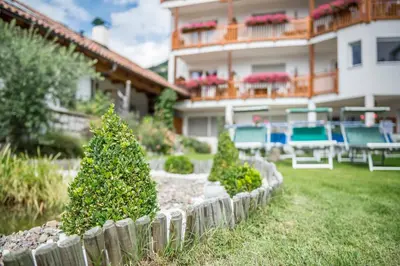a house with a yard with chairs and a fence at Hotel Meinhardt in Schenna