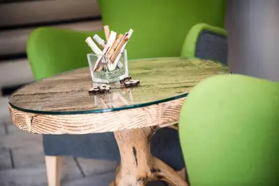 a wooden table with green chairs and a glass at Hotel Meinhardt in Schenna