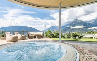 a hot tub on a patio with mountains in the background at Hotel Meinhardt in Schenna