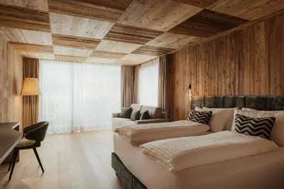 two beds in a room with wooden walls at Luxury B&B August in Ortisei