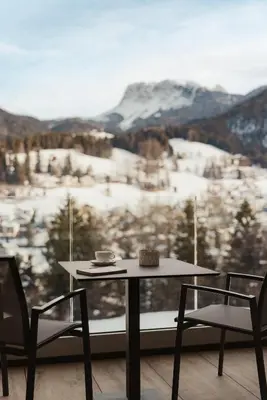 a table and chairs with a view of a snowy mountain at Luxury B&B August in Ortisei