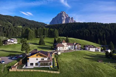 a house on a hill with a mountain in the background at Residence La Selva in Selva di Val Gardena