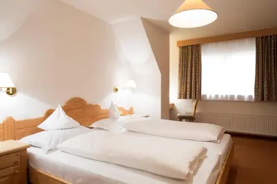a bedroom with two beds with white sheets and a window at Residence La Selva in Selva di Val Gardena