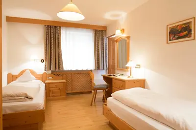 a hotel room with two beds and a desk at Residence La Selva in Selva di Val Gardena