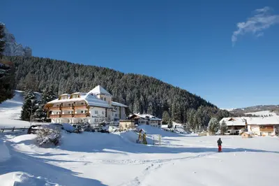 a person standing in the snow in front of a lodge at Residence La Selva in Selva di Val Gardena