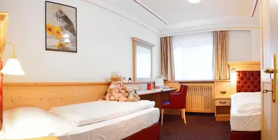 a hotel room with two beds and a desk at Residence Isabell in Selva di Val Gardena