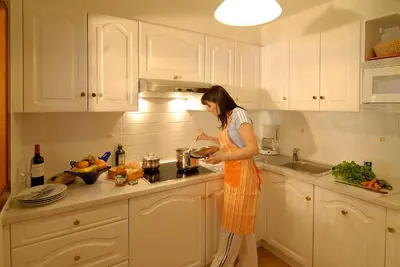 a woman standing in a kitchen preparing food at Residence Villa Gran Baita in Selva di Val Gardena