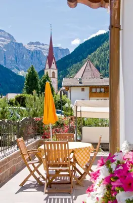 a patio with two chairs and a table and a yellow umbrella at Residence Villa Gran Baita in Selva di Val Gardena
