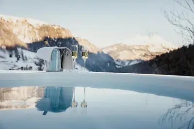 a hot tub with wine glasses in the snow at Hotel Alpenrose in Arabba