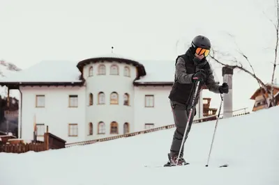a person on skis in the snow in front of a building at Hotel Alpenrose in Arabba