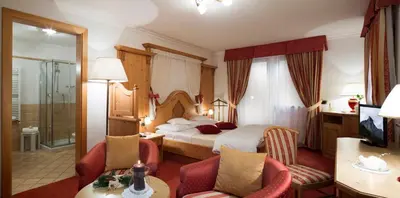 a hotel room with a bed and two chairs at Hotel Alpenrose in Arabba