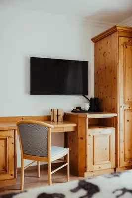 a desk with a chair and a television on a wall at Hotel Alpenrose in Arabba