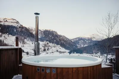 a jacuzzi tub with a view of a snowy mountain at Hotel Alpenrose in Arabba