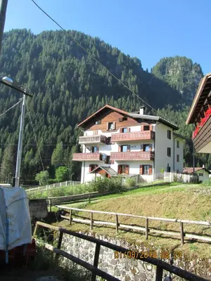 a building on a hill with mountains in the background at Ciesa Dei Maestri in Sottoguda