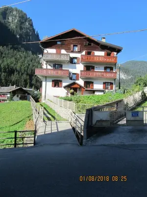 a large building on a hill next to a road at Ciesa Dei Maestri in Sottoguda