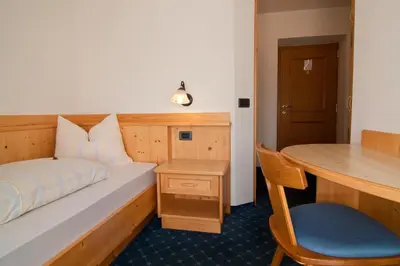 a bedroom with a bed and a desk and a table at Pension Enzian in Badia