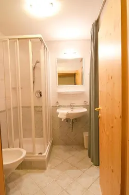 a bathroom with a sink and a shower at Pension Enzian in Badia