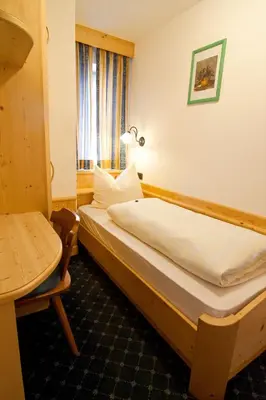 a bedroom with a bed and a table and a window at Pension Enzian in Badia