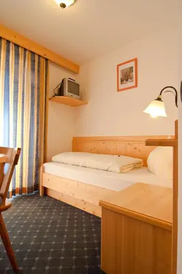 a hotel room with two beds and a desk at Pension Enzian in Badia