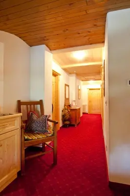 a hallway with a bench and a red carpet at Pension Enzian in Badia