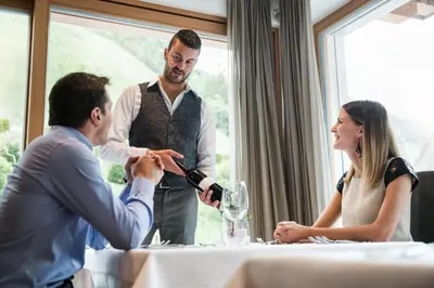a man is pouring a glass of wine at a table at Hotel Alcialc in La Valle