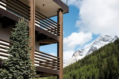 a christmas tree in front of a building with a snow covered mountain at Hotel Alcialc in La Valle