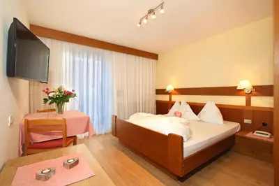a hotel room with a bed and a table at Hotel Garni Savoy - new opening in Castelrotto