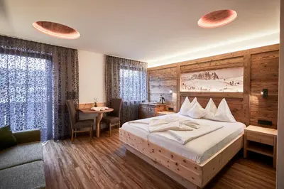 a hotel room with a bed and a table and a desk at Hotel Garni Savoy - new opening in Castelrotto