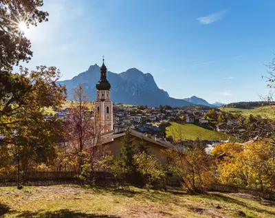 a view of a town and a church with a mountain in the background at Hotel Garni Savoy - new opening in Castelrotto