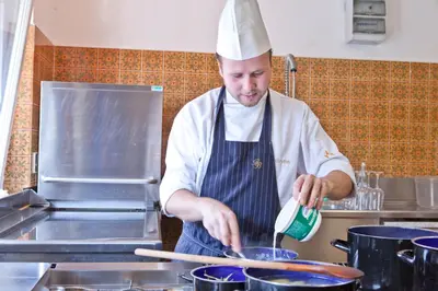 a chef in a kitchen preparing food on a pan at Parkhotel Plauserhof in Plaus