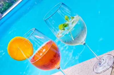 two glasses of cocktails next to a swimming pool at Parkhotel Plauserhof in Plaus