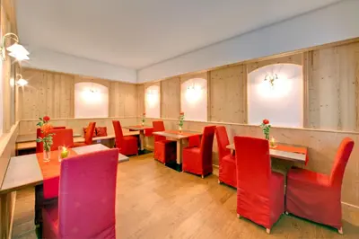 a restaurant with red chairs and tables in a room at Parkhotel Plauserhof in Plaus