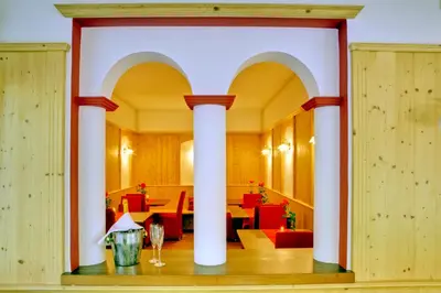 a dining room with columns and red chairs at Parkhotel Plauserhof in Plaus