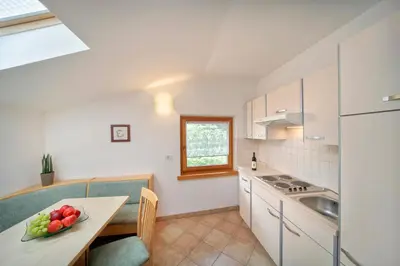 a kitchen with white cabinets and a table with a bowl of fruit at Sonnenhof in Rifiano