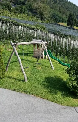 a park with a swing set in the grass at Sonnenhof in Rifiano
