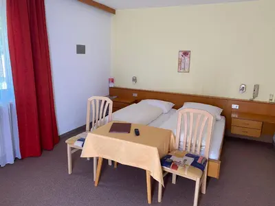 a bedroom with a bed and a table and chairs at Pension Thalerhof in Rifiano