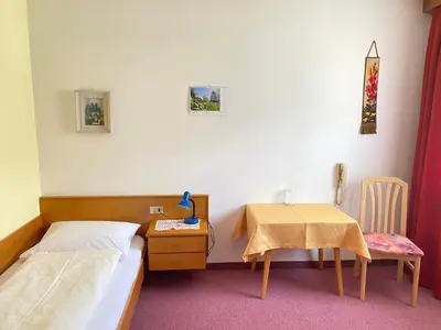 a bedroom with a bed and a table and a table and chair at Pension Thalerhof in Rifiano