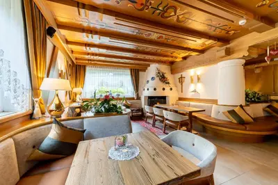 a living room with a wooden table and a fireplace at Hotel Gran Paradis in Campitello di Fassa