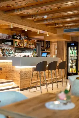 a bar with four chairs in front of a counter at Hotel Gran Paradis in Campitello di Fassa